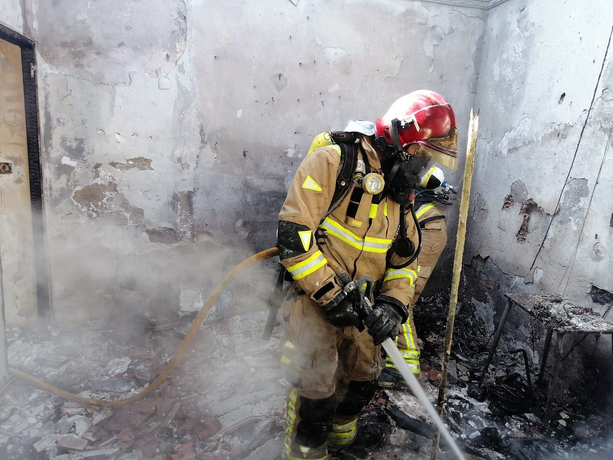 Bomberos sofocando el incendio en una vivienda de Totana