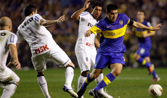 Román Riquelme intenta zafarse del marcaje de dos rivales en el partido de ida de la final jugado en La Bombonera