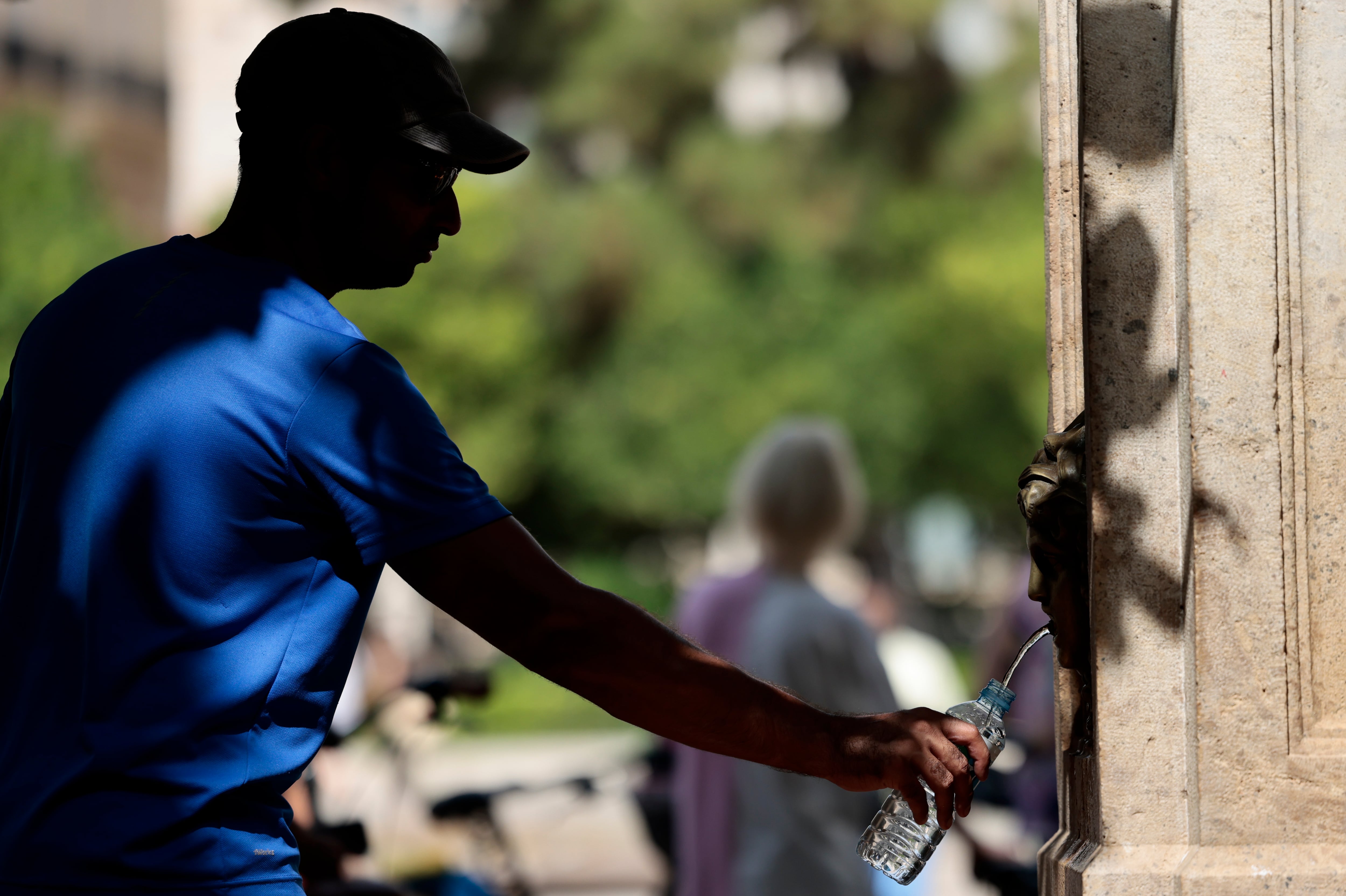 Un hombre rellena una botella de agua en una fuente pública de València