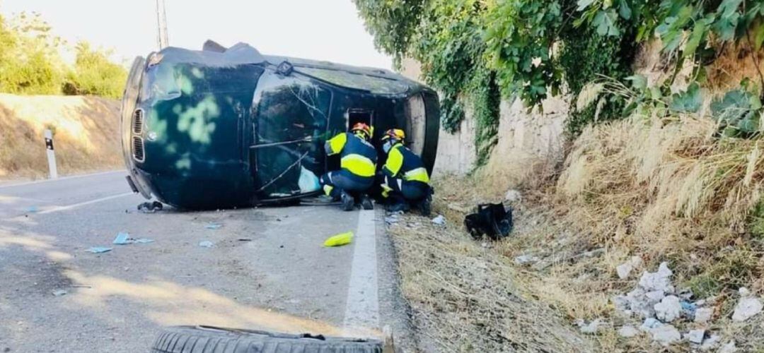 Bomberos examinando el vehículo accidentado.
