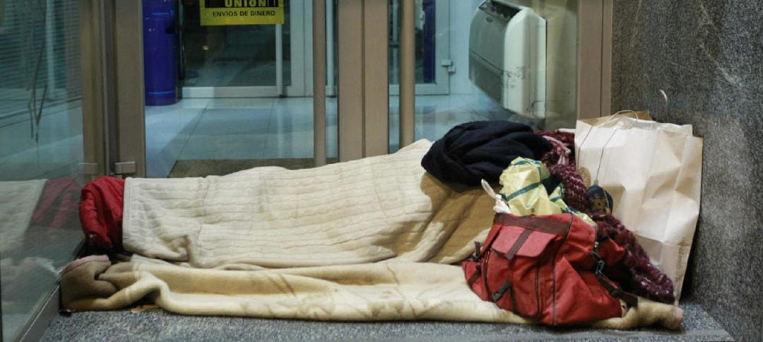 Un indigente se dispone a pasar la noche a las puertas de una entidad bancaria. 