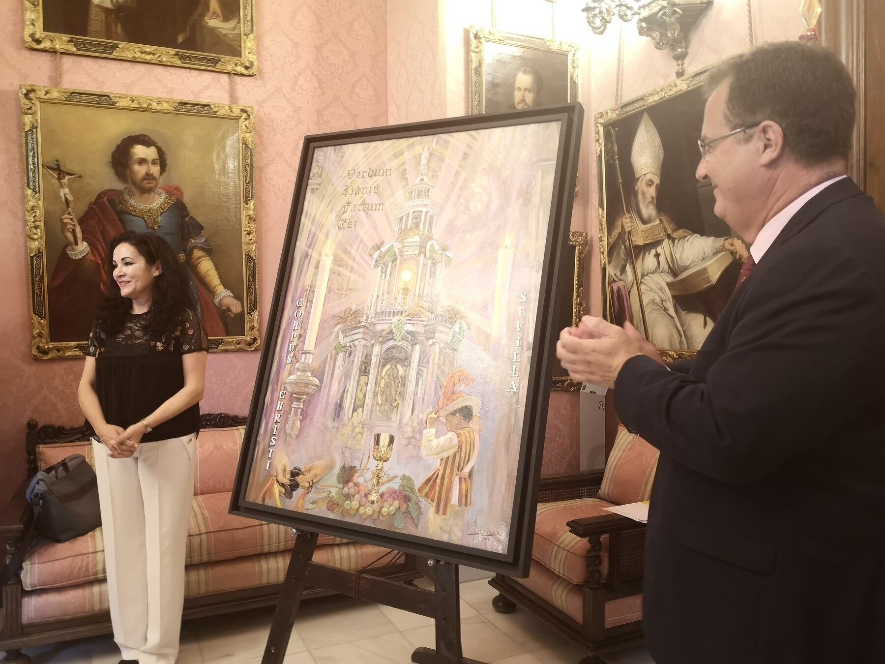 La pintora Isabel Castilla, aplaudida por el delegado municipal de Fiestas Mayores, Juan Carlos Cabrera, posa junto a su cartel del Corpus