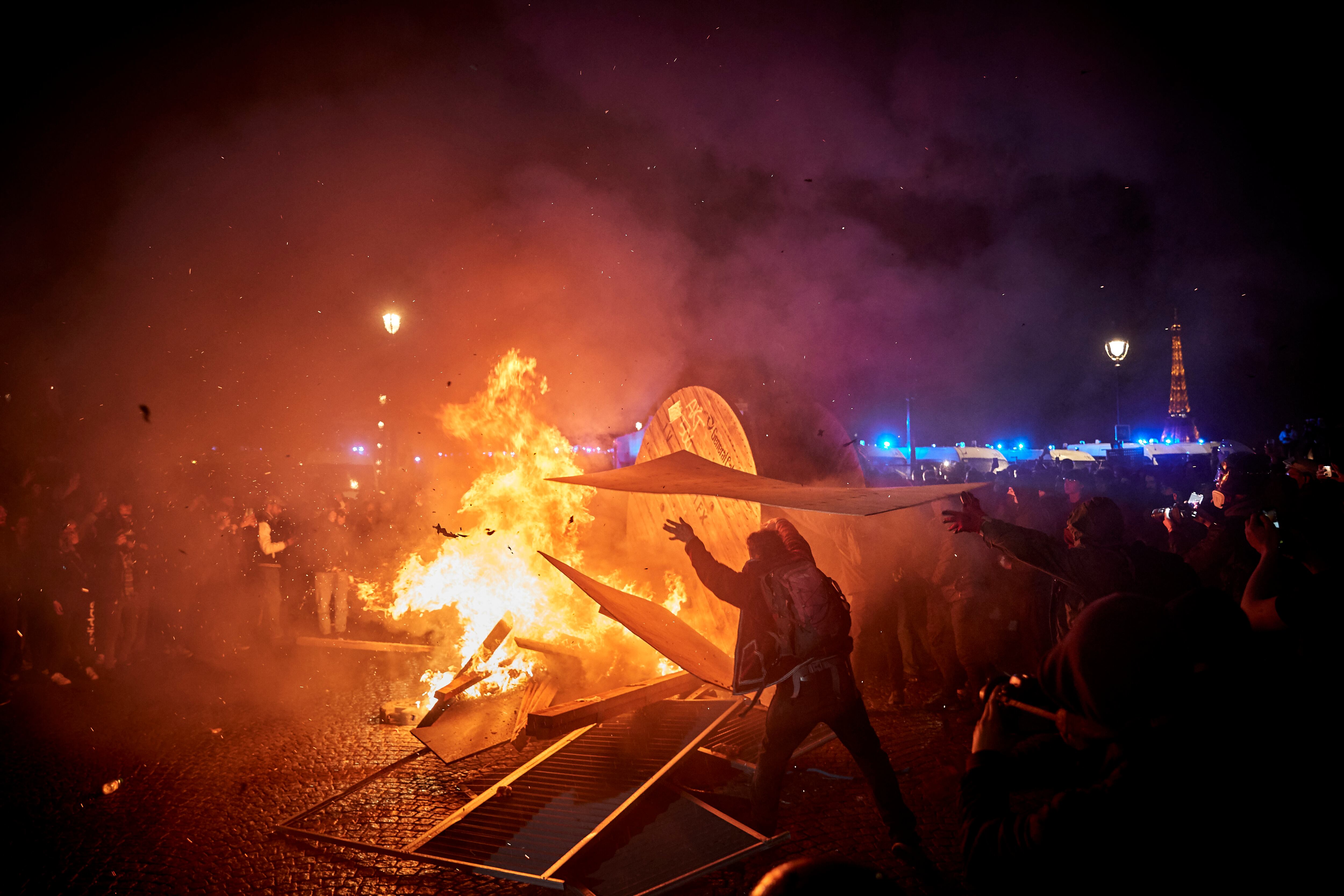 Un manifestante lanza un trozo de madera al fuego delante de la Asamblea Nacional francesa durante las protestas contra la reforma de las pensiones