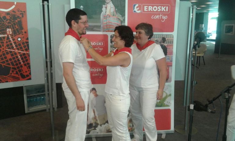 Eva Mendiluce, gerente del hipermercado Eroski pamplona, anuda el pañuelico de Honor a Sergio Espuelas, en representación del Grupo de Danzas Oberena