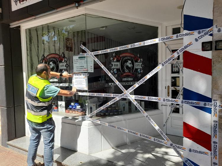 Un agente de Policía Nacional precinta la peluquería en la calle Palma