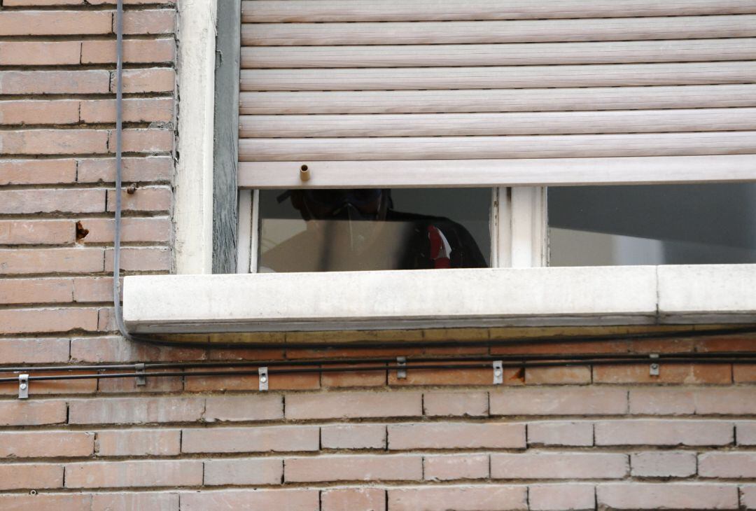 Un hombre con mascarilla en la ventana