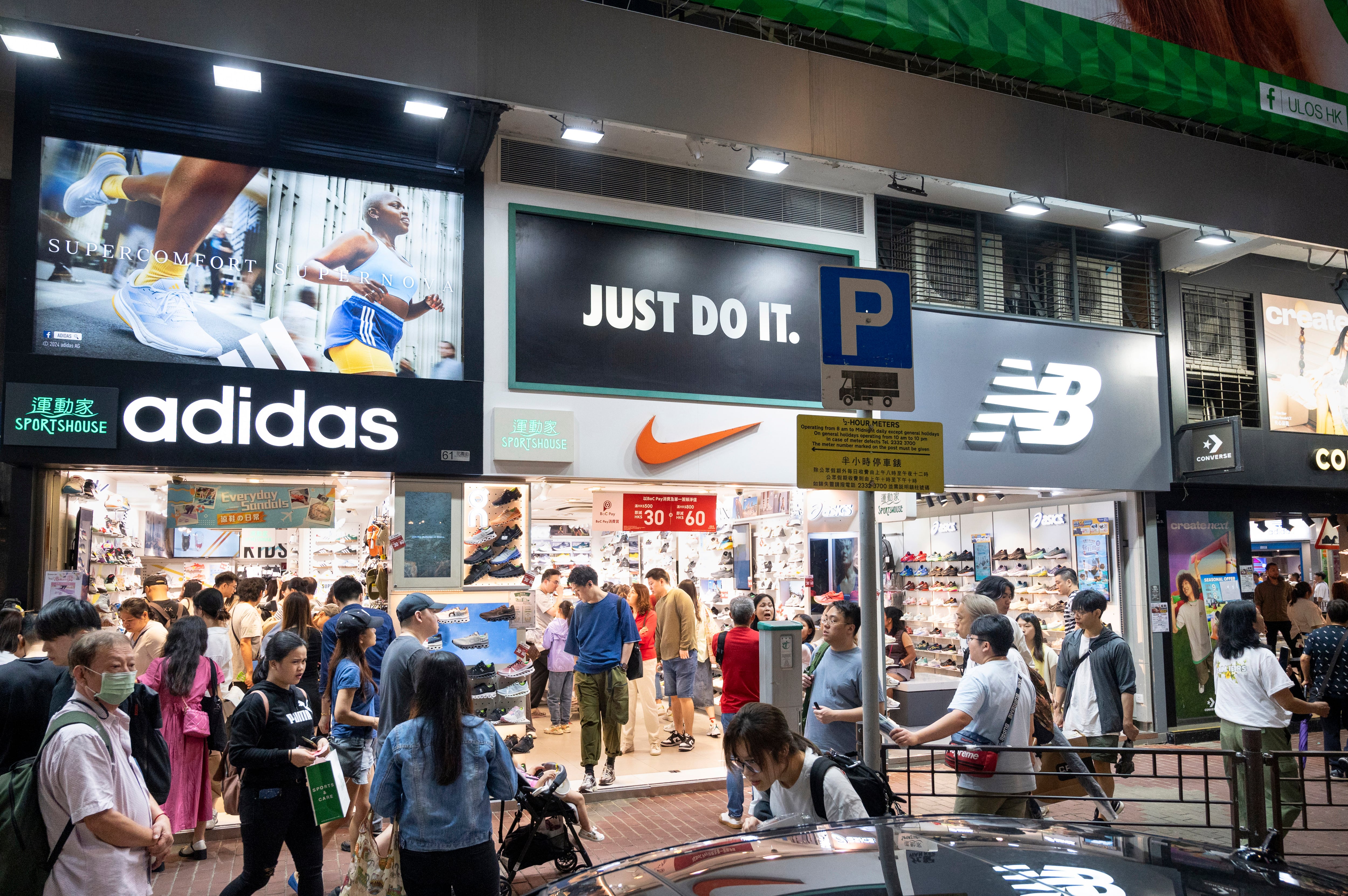 Compradores en una calle poblada de tiendas de ropa deportiva