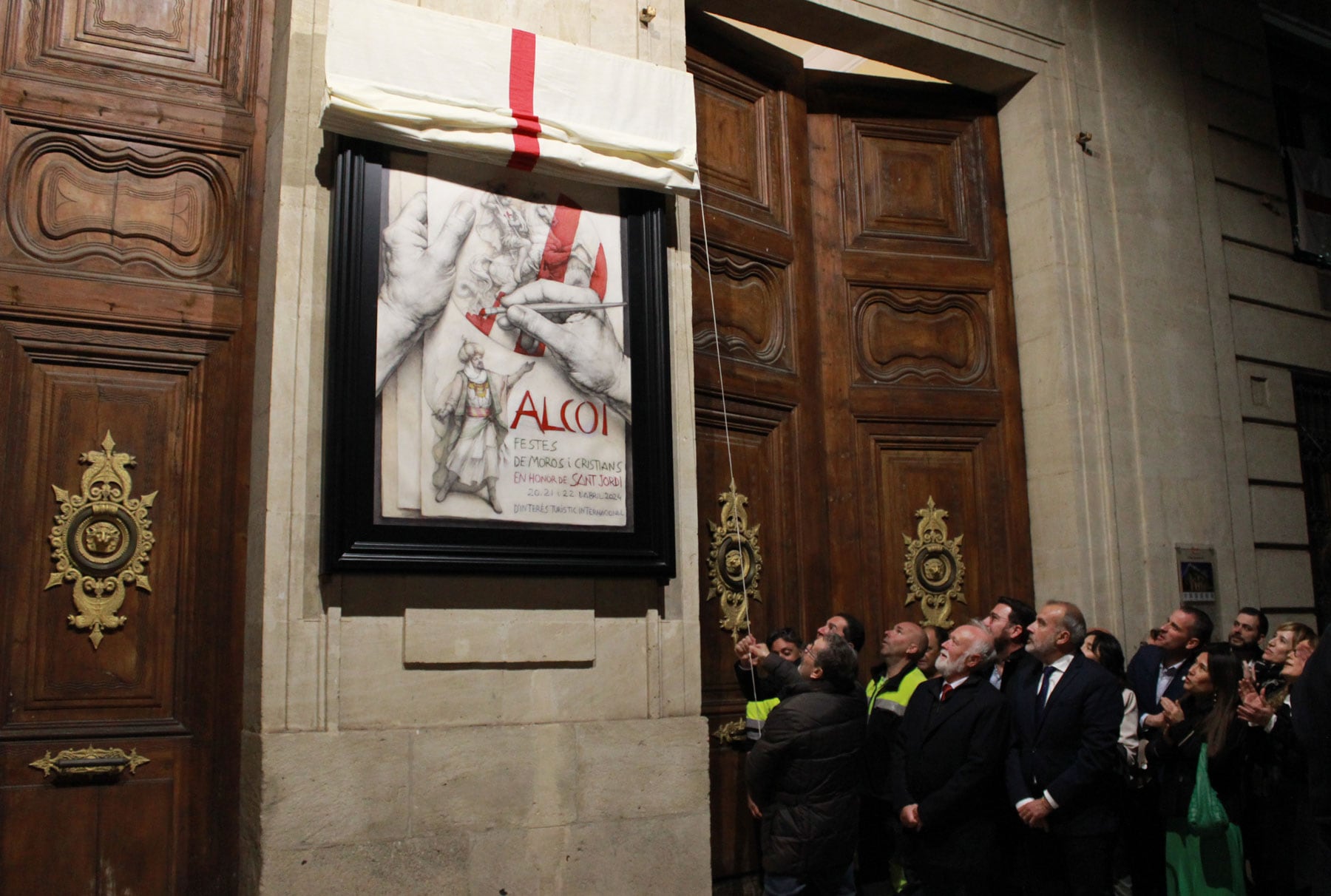 Instante en el que el alcalde Toni Francés y el autor de la obra, Joan Castejón, descubren el cartel de Fiestas de Moros y Cristianos de Alcoy 2024