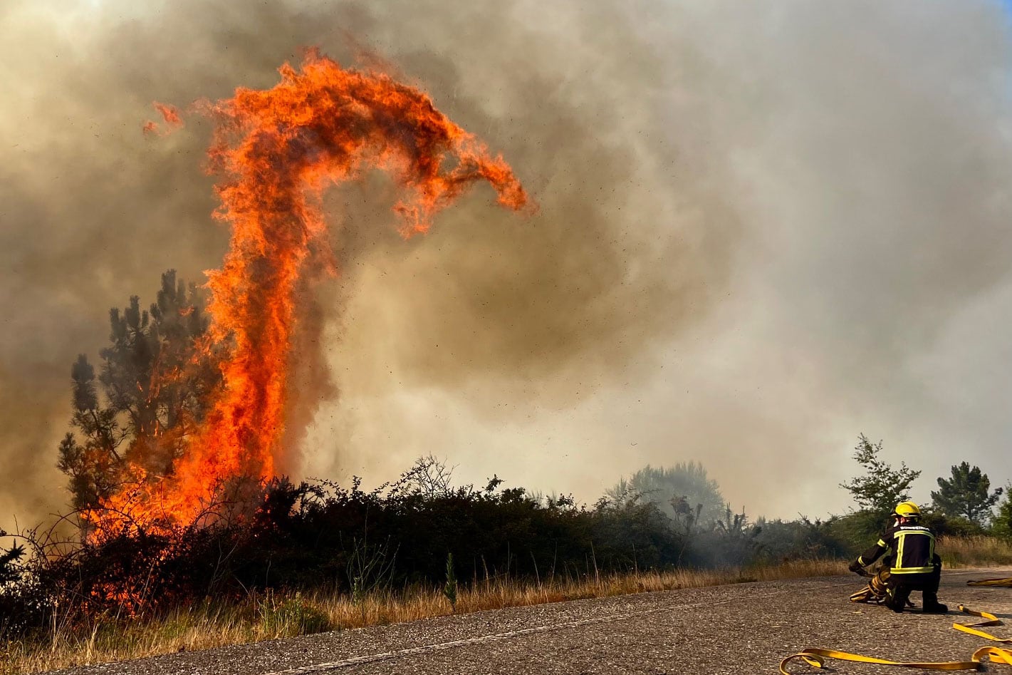 -FOTODELDÍA- A CAÑIZA (PONTEVEDRA), 31/07/2022.- Efectivos de bomberos trabajan este domingo en la extinción de un incendio forestal en la carretera N120, actualmente cortada por las llamas, en A Cañiza (Pontevedra). EFE/Sxenick