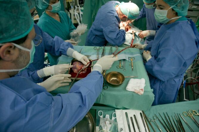 En primer término el cirujano Enrique Fulquet prepara el corazón donado mientras al fondo el cirujano Salvatore Di Stefano extrae el corazón enfermo