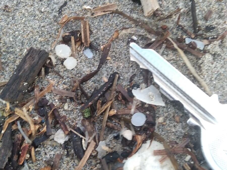 Restos de pellets en una playa asturiana, en una imagen facilitada por el Gobierno del Principado. Una llave sirve de referencia para calcular el tamaño de las pequeñas bolas blancas.