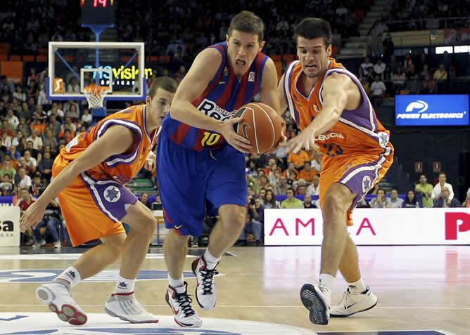 El escolta esloveno del Regal FC Barcelona, Jaka Lakovic intenta entrar a canasta ante los jugadores del Power Electronics Valencia, Marc Fernández y José Simeón, durante el partido correspondiente a la tercera jornada de la liga ACB de baloncesto jugado en el pabellón de la Fuente de San Luis de Valencia