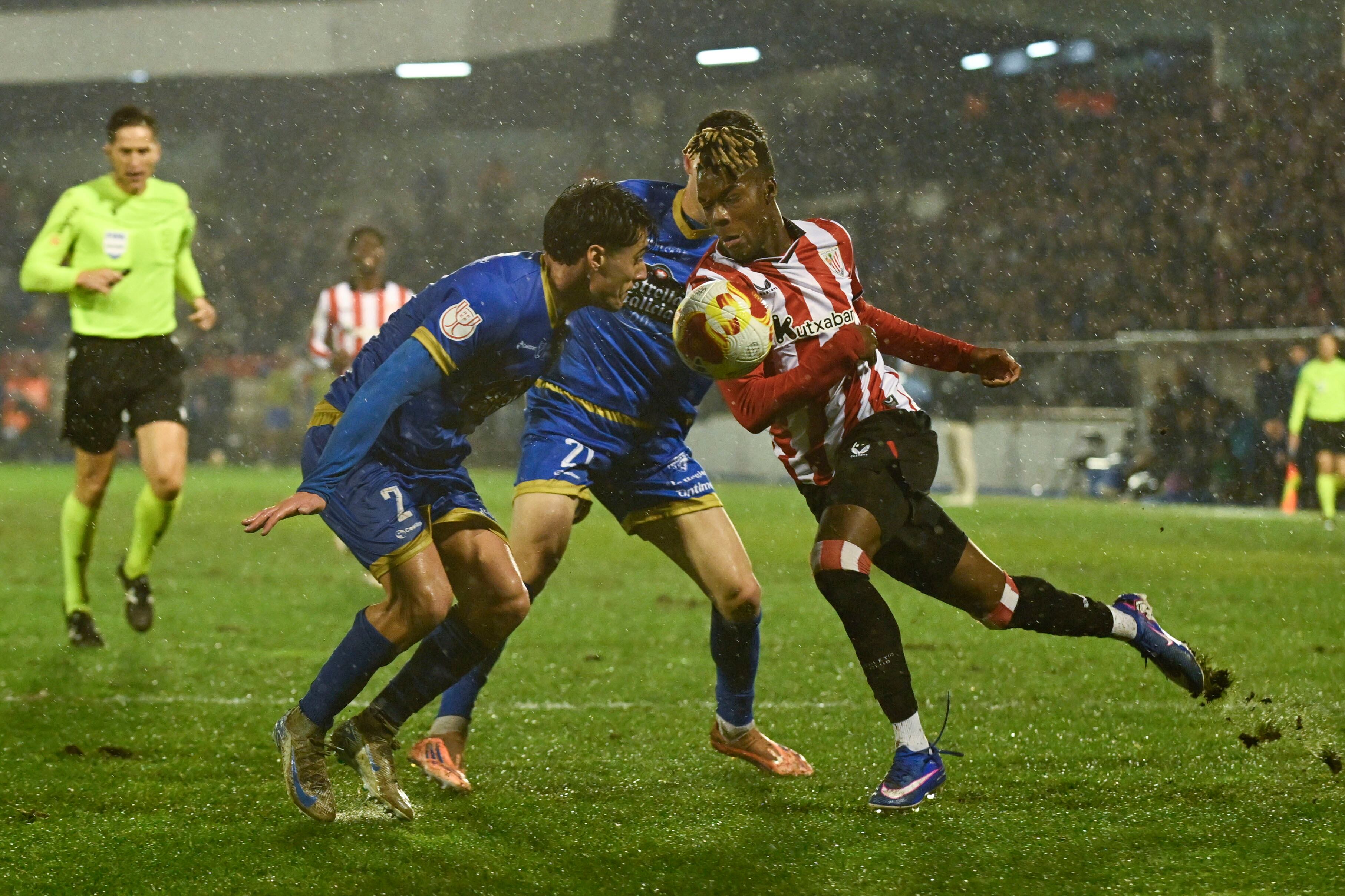 OURENSE, 18/12/2025.- El delantero del Athletic Nico Williams (d) pelea un balón con Enol Coto (i), del Ourense, durante el partido de dieciseisavos de final de la Copa del Rey que Ourense CF y Athletic Club disputan este jueves en el estadio de O Couto. EFE/Brais Lorenzo
