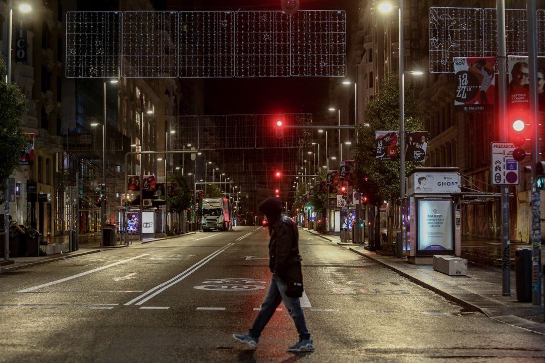 Un chico cruza una calle del centro de Madrid durante la primera noche de toque de queda en la capial (España)