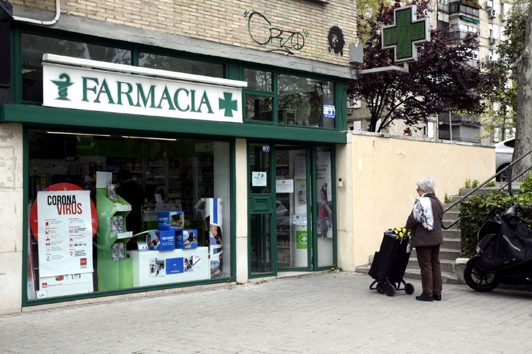 Una mujer espera en la calle como medida de precaución a entrar en una farmacia