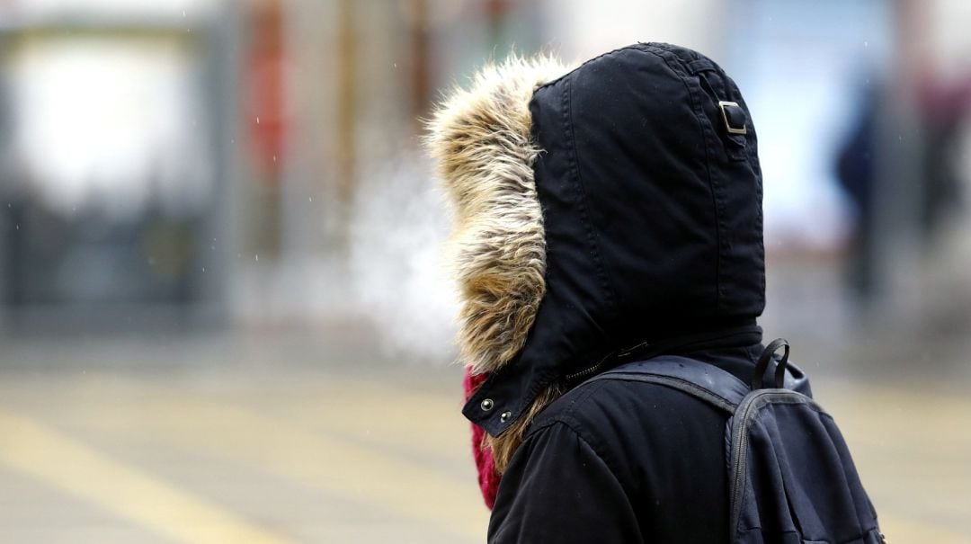 Una persona camina abrigada por la calle.