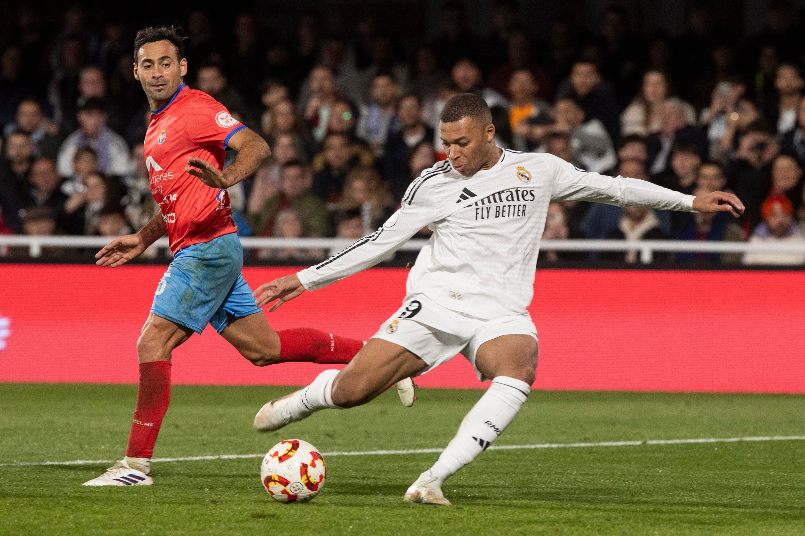 CARTAGENA (MURCIA), 06/01/2025.- El delantero francés del Real Madrid Kylian Mbappé (d) dispara a puerta ante el jugador de la Deportiva Minera Omar Perdomo (i) durante el partido correspondiente a los dieciseisavos de final de la Copa del Rey, que están disputando este lunes en el estadio Cartagonova en Cartagena. EFE/Marcial Guillén
