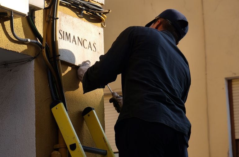 Un operario retirando la placa de la Calle Simancas 