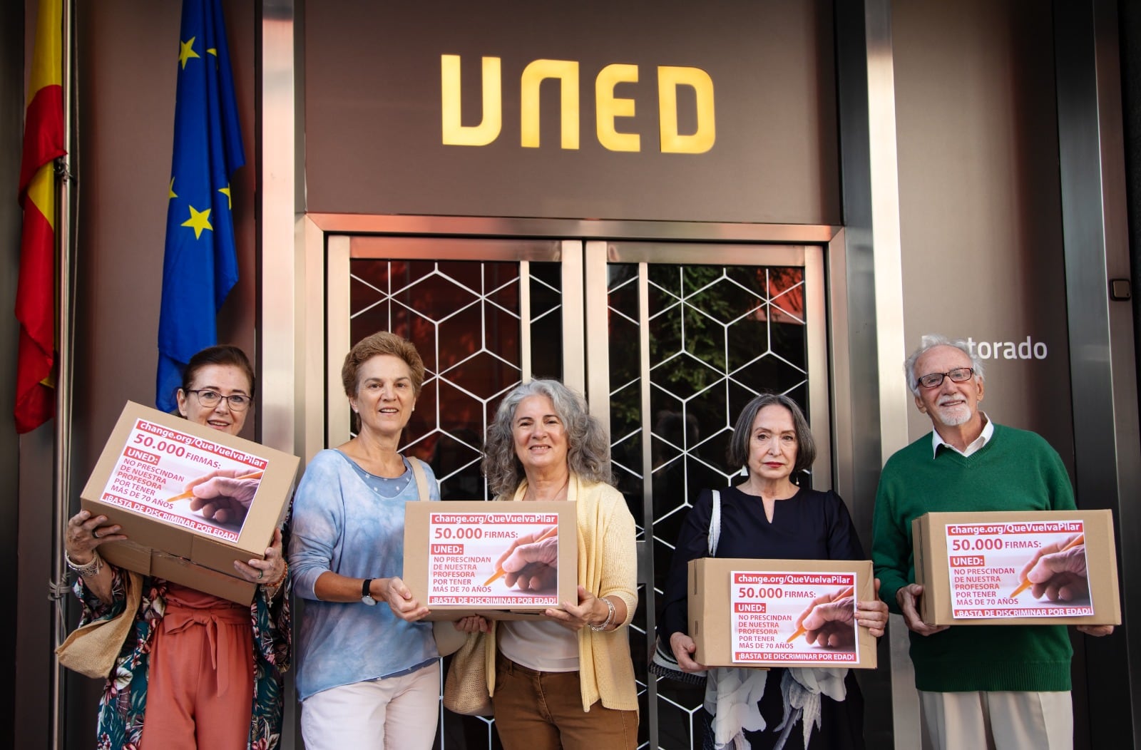 José Luis Martín (dcha), impulsor de las petición para conseguir que se renueve a la docente de 70 años (2a drcha), se concentra con ella y otras alumnas frente a las puertas del rectorado de la UNED en Madrid