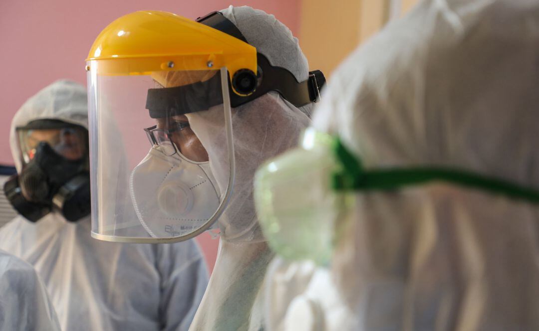 Tres personas protegidas con buzos y pantallas protectoras contra el coronavirus.