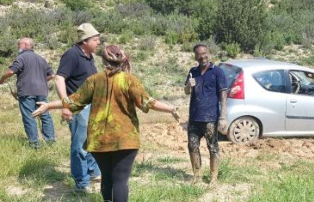 La pareja junto al alcalde, Ovidio Ortín, mientras trataban de sacar el vehículo del barro en el que había quedado atrapado, con ayuda de un agricultor (al fondo).