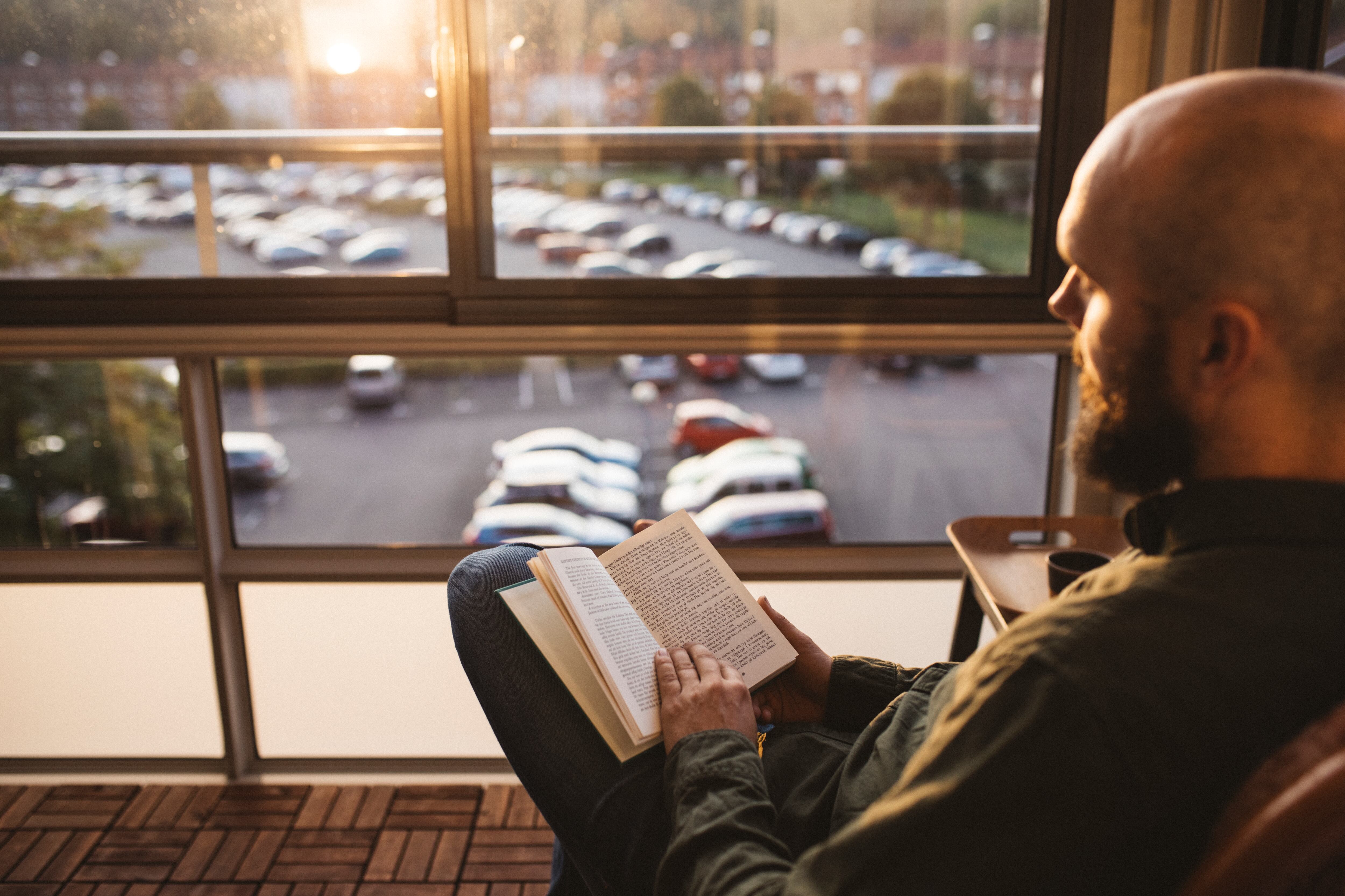 Un hombre leyendo un libro en una terraza.