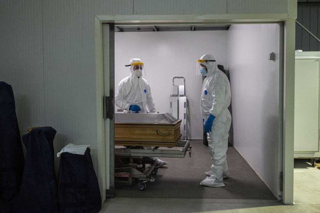 Funerarios con trajes de protección colocan el cuerpo de una víctima del Covid-19