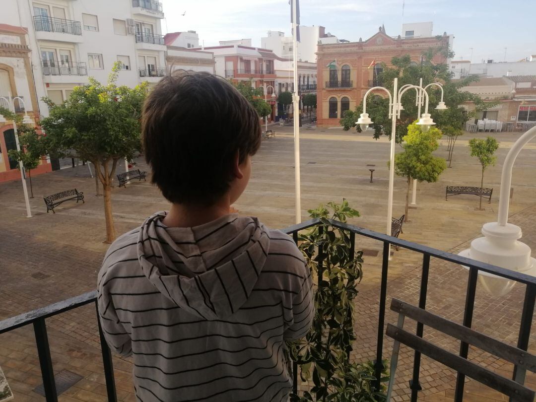 Marcos (9 años), mira la plaza desde el balcón de su casa donde lleva casi 40 días sin salir por el confinamiento