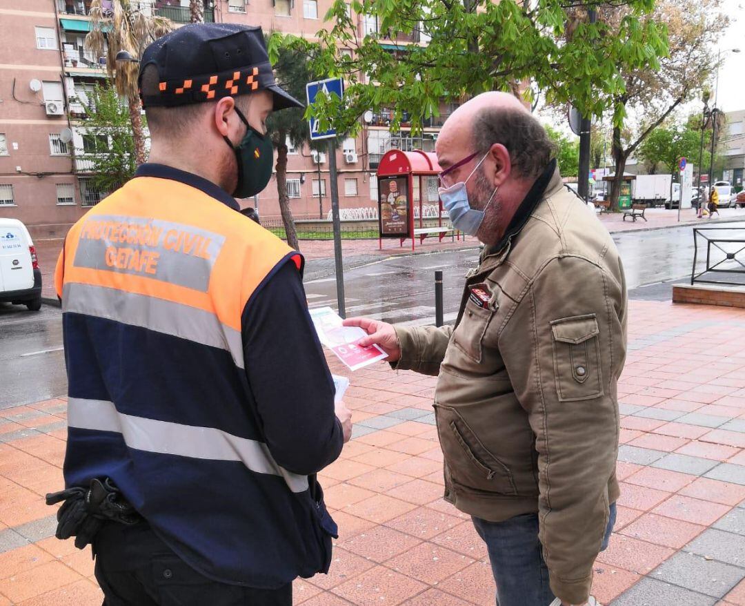 Un voluntario de Protección Civil de Getafe entrega información a un vecino de Las Margaritas sobre las limitaciones a la movilidad que siguen vigentes.