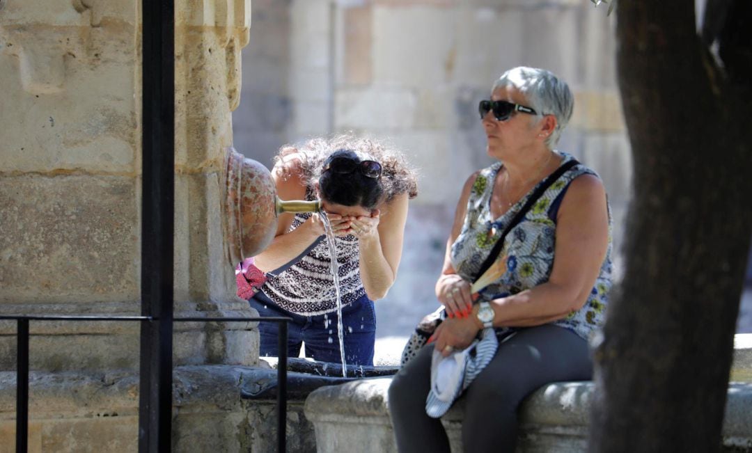 Una turista se refresca en una de las fuentes del patio de los Naranjos de la Mezquita-Catedral de Córdoba.