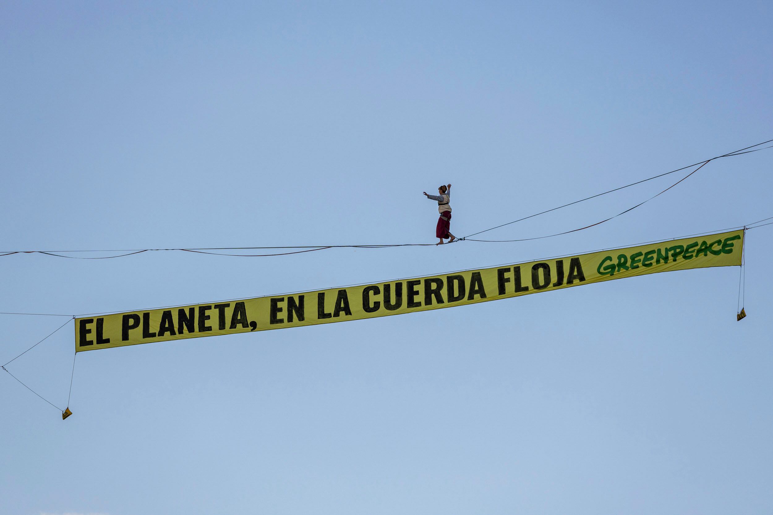 Una activista de Greenpeace ha recorrido una cinta a 30 metros de altura sobre la plaza de España en Madrid.