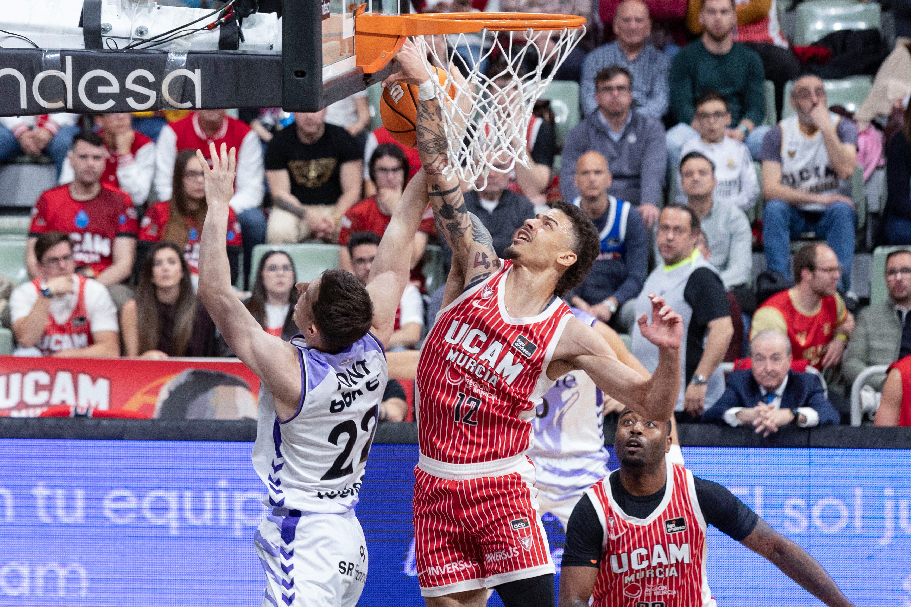 El base estadounidense de UCAM Murcia, Jonah Radebaugh, hace un mate al escolta de Surne Bilbao, Aleix Font, durante el partido de la vigésima cuarta jornada la liga Endesa que están disputando este sábado en el Palacio de los Deportes de Murcia. EFE/Marcial Guillén.
