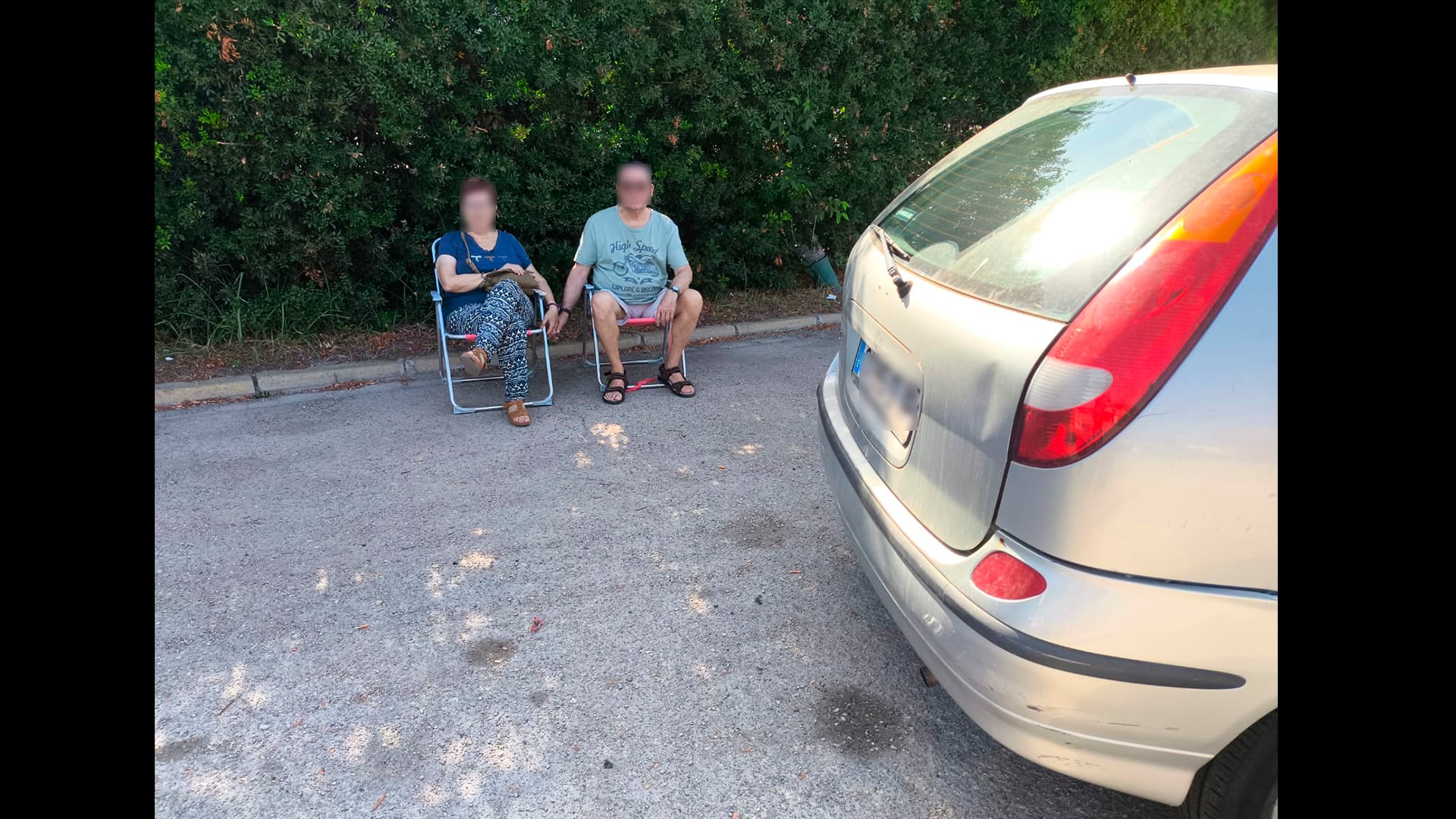 Una pareja espera con sus sillas de playas a su turno en el ITV de Gandia.