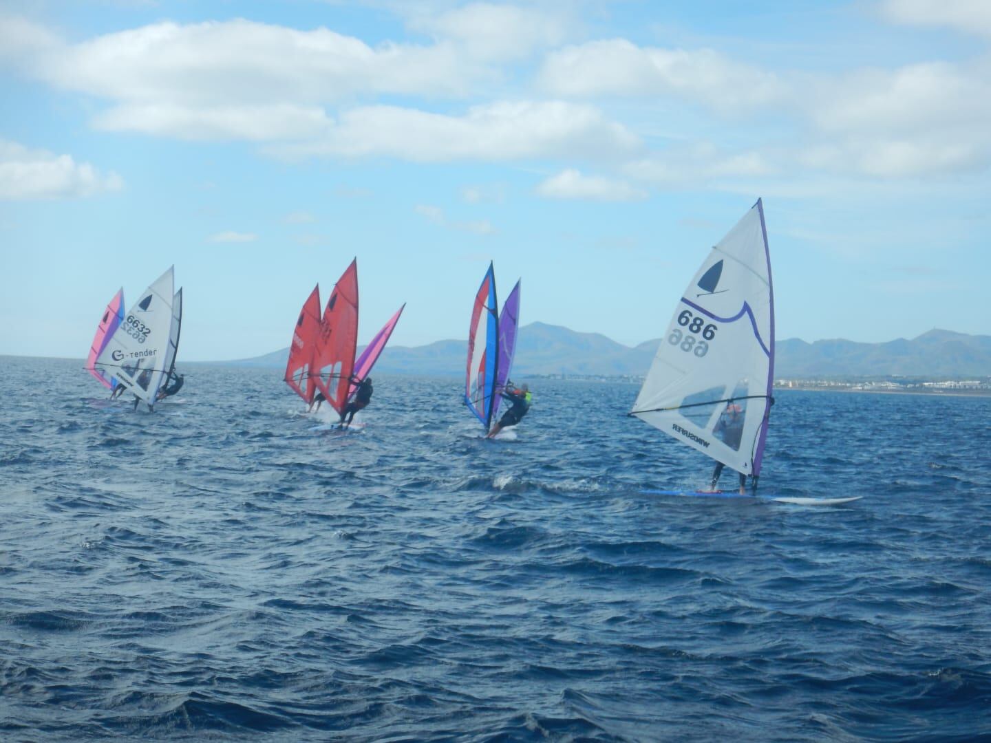 Regatistas a bordo de sus tablas de windsurf en aguas de Lanzarote.