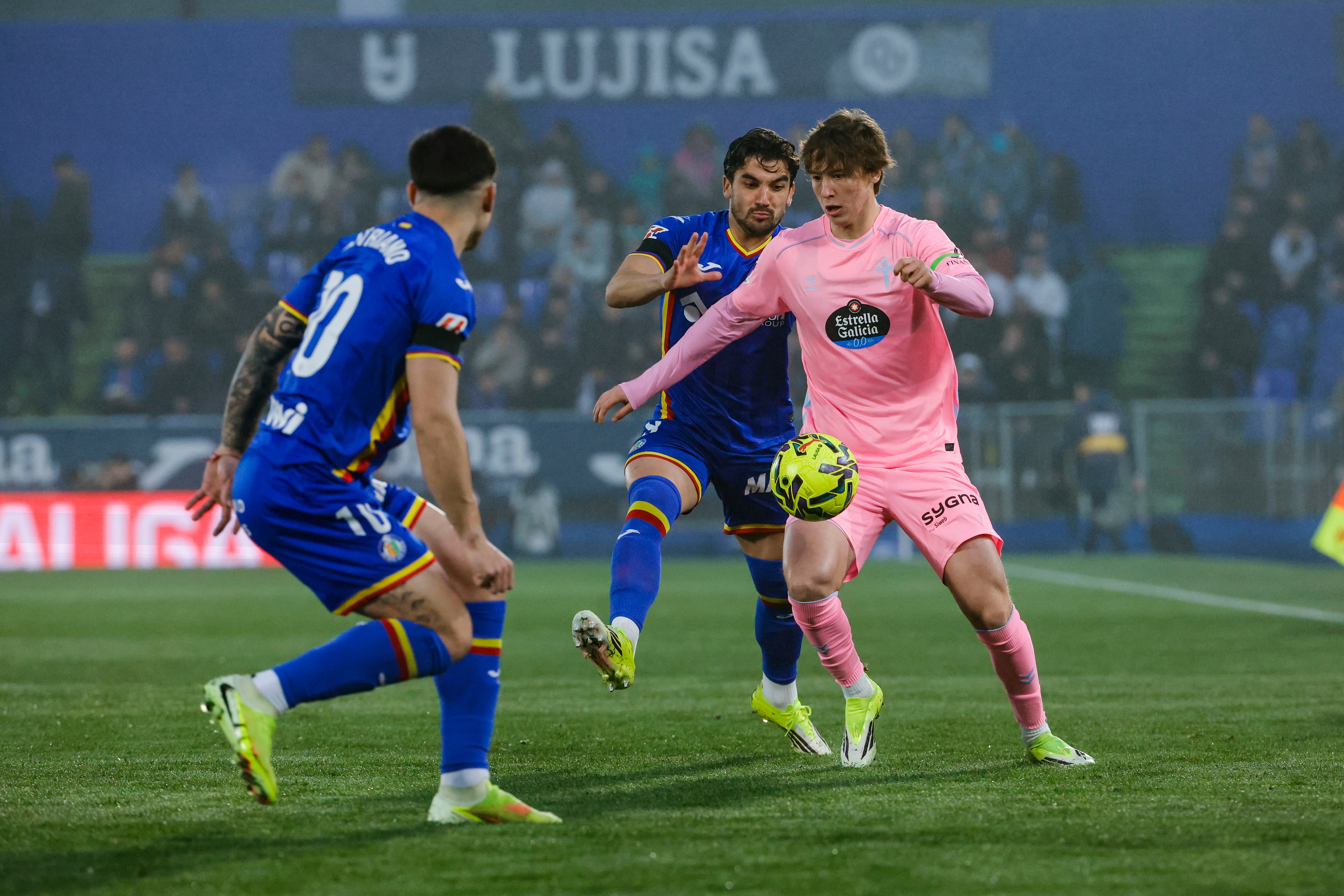 GETAFE, 01/02/2026.- El centrocampista del Celta, Fer López (d), intenta llevarser el balón ante los jugadores uruguayos del Getafe, Mauro Arambarri y Martín Satriano (i), durante el encuentro correspondiente a la jornada 22 de Laliga EA Sports que disputan hoy Domingo en el Coliseum de Getafe. EFE / Zipi Aragón.