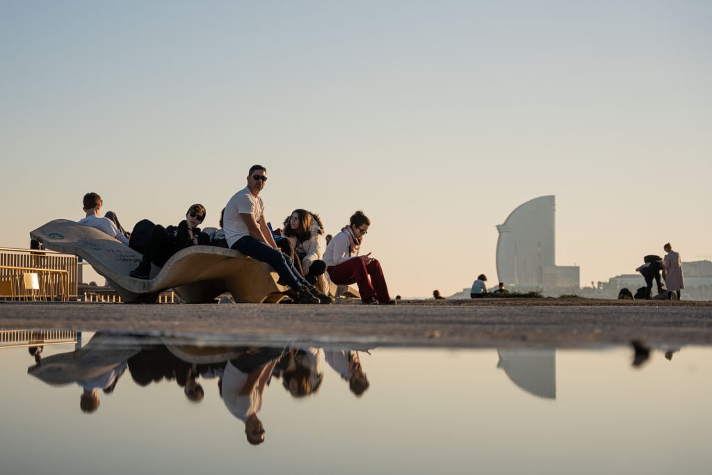 Varias personas disfrutan del sol en la playa de Barcelona en pleno mes de enero.