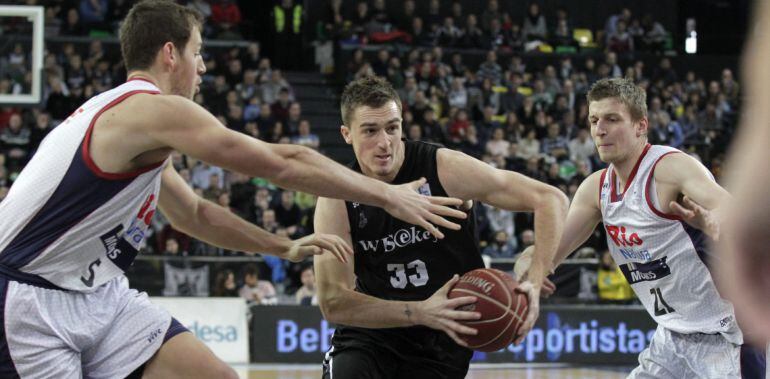 GRA051. BILBAO, 28/12/2014.- El escolta serbio del Bilbao Basket, Danilo Andjusic (c), intenta penetrar a canasta ante la oposición del alero polaco del Rio Natura Monbus Obradoiro, Adam Waczynski (d), y el pívot Daniel Miller (i), durante el partido de la decimotercera jornada de la Liga Endesa disputado entre ambos equipos hoy en la cancha de Bilbao Arena. EFE/Alfredo Aldai