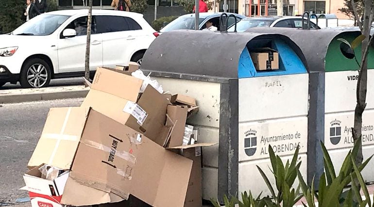 Cajas de cartón junto a un contenedor de papel