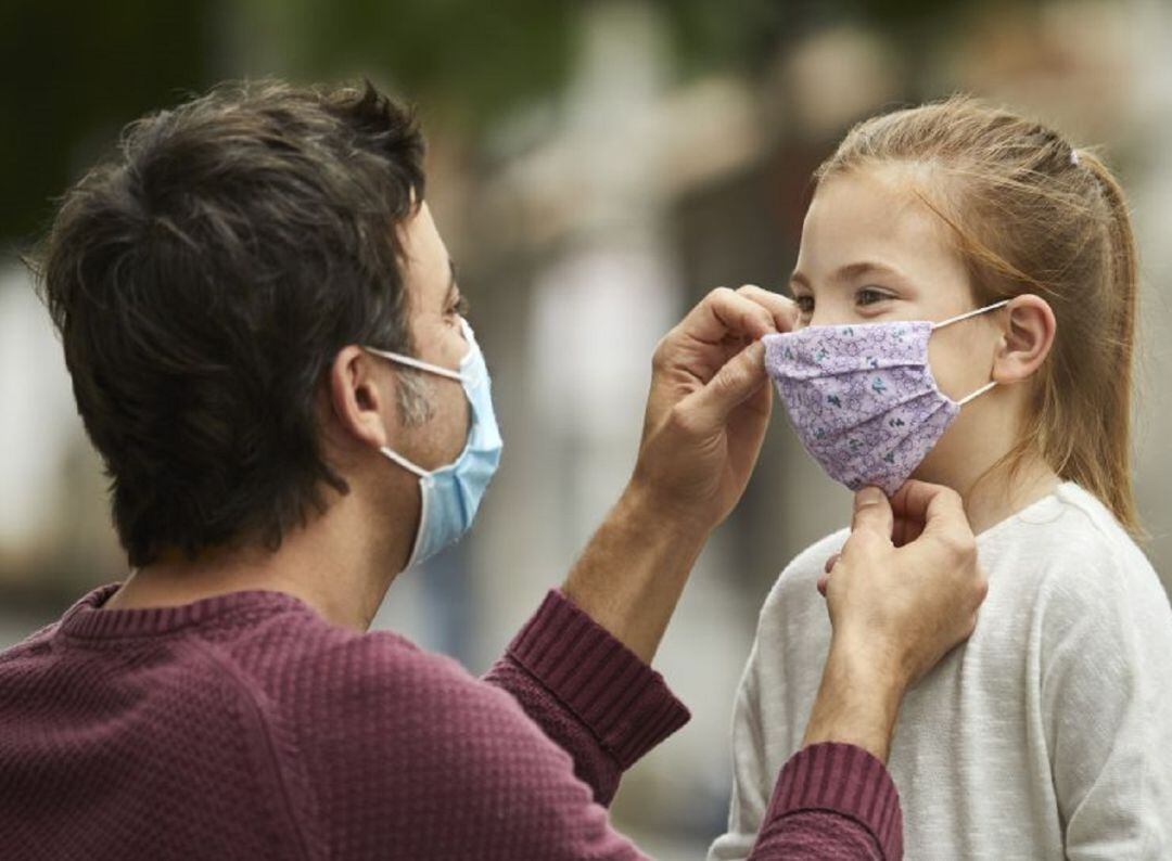 Padre colocando mascarilla a su hijo