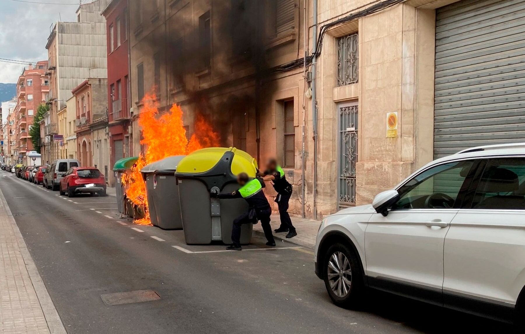 Agentes de la Policía Local de Alcoy separando el contenedor de envases para evitar que llegaran las llamas.