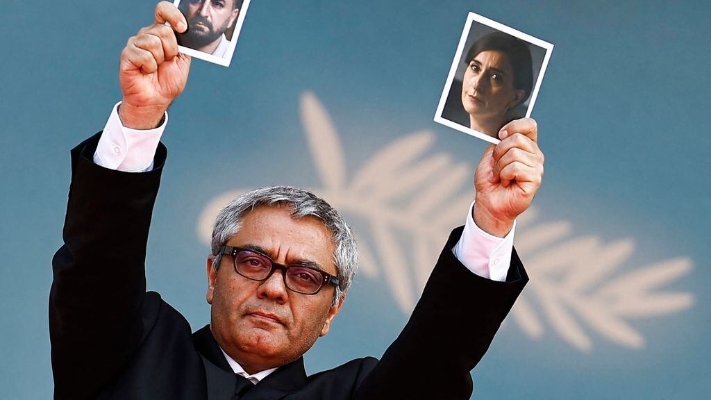 Iranian director Mohammad Rasoulof holds a portrait of Iranian actress Soheila Golestani  (R) and Iranian actor Missagh Zareh (L) as he arrives for the screening of the film &quot;The Seed of the Sacred Fig&quot; at the 77th edition of the Cannes Film Festival in Cannes, southern France, on May 24, 2024. (Photo by Sameer Al-Doumy / AFP)