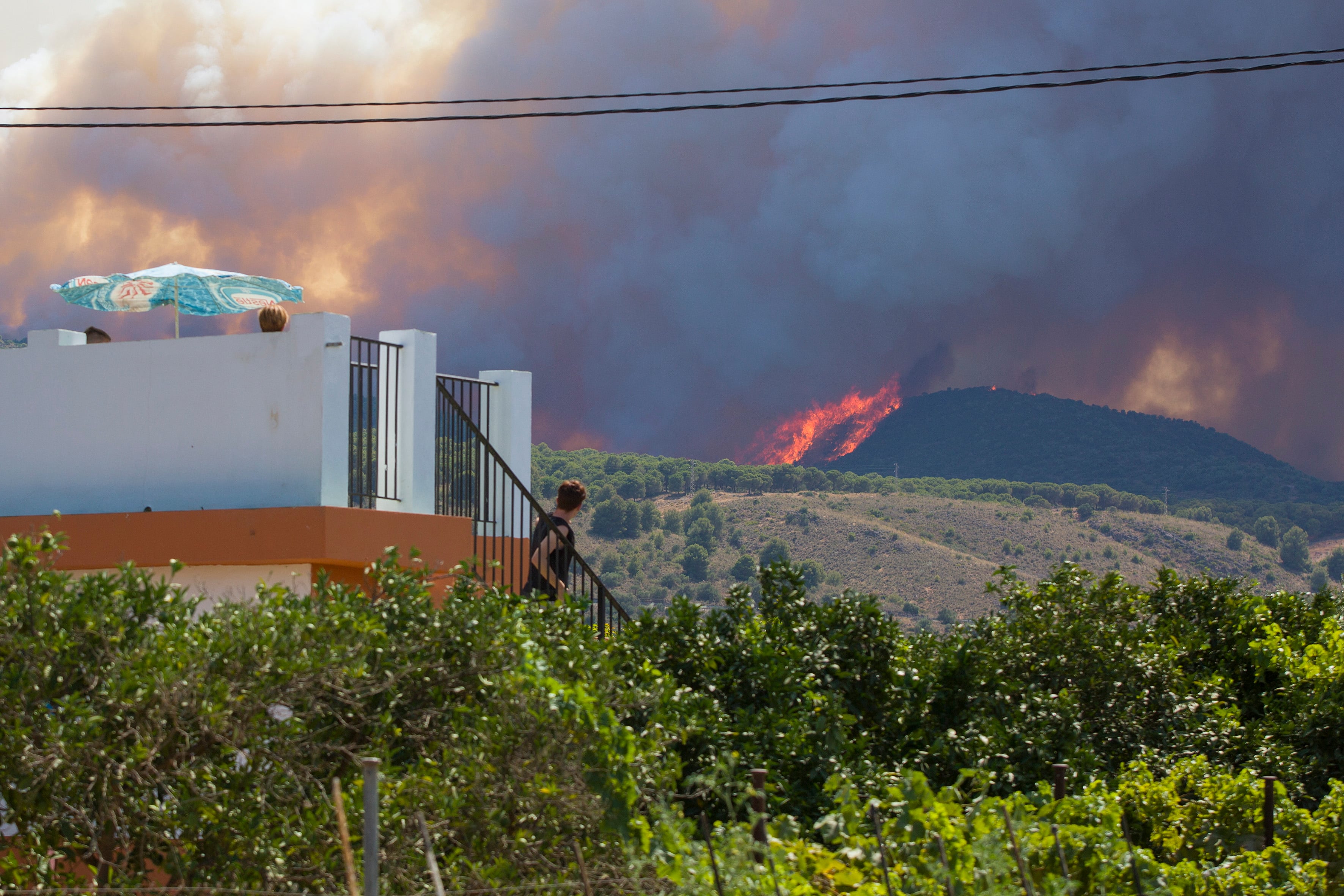 GRAFAND1667. ALHAURÍN EL GRANDE (MÁLAGA), 15/07/2022.- Varios vecinos contemplan el incendio declarado este mediodía en el paraje El Higuerón de Mijas (Málaga) 