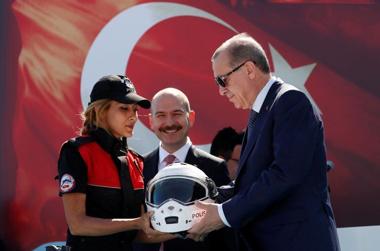 El presidente turco recibe un casco como obsequio de manos de una agente de policía, durante una ceremonia en Estambul.  