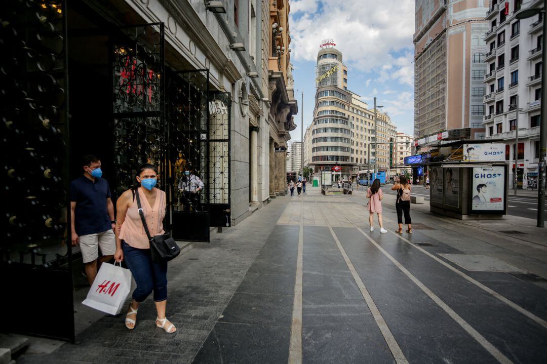 Varias personas salen de una tienda de moda en la Gran Vía durante la fase 1 de la desescalda.