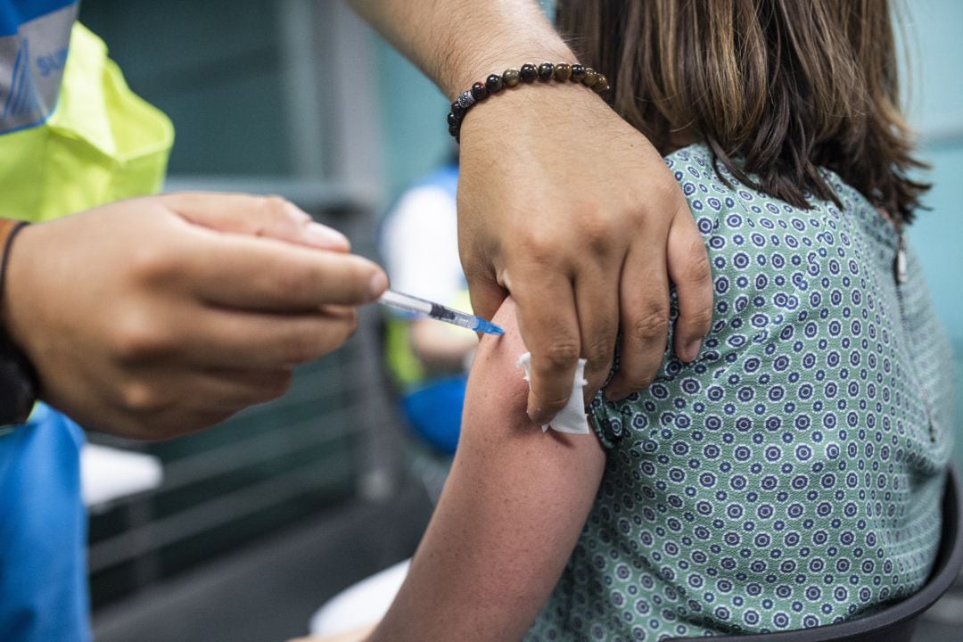 Un sanitario administra una dosis de la vacuna de Pfizer a una mujer en el Wizink Center.