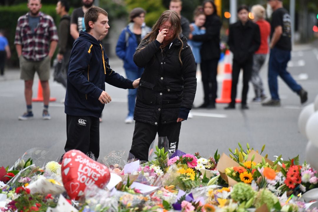 Personas dejando flores en la puerta de una de las mezquitas en Christchurch, Nueva Zelanda