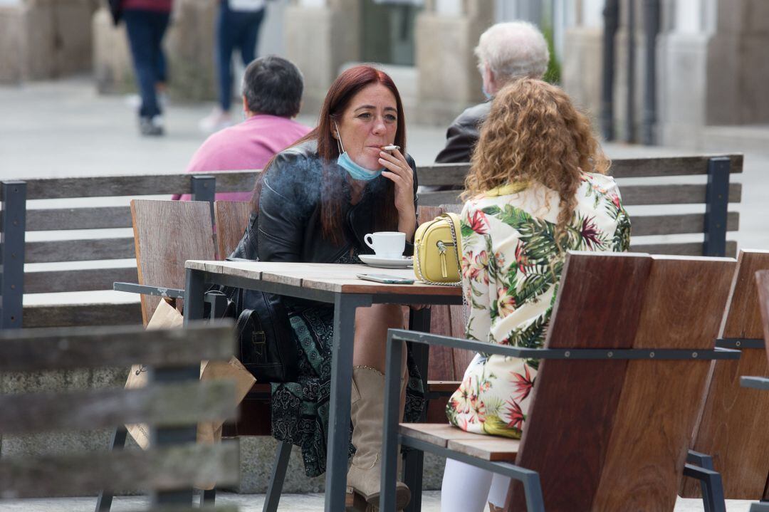 Una mujer fumando una terraza en Galicia