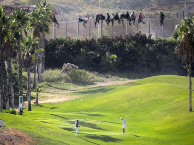 Al menos doce inmigrantes, encaramados en la valla de Melilla frente al campo de golf situado al lado de la alambrada que separa la ciudad autonoma de Marruecos