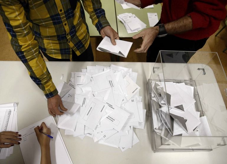 El presidente de una mesa electoral deposita los votos de la urna sobre una mesa para proceder a su recuento.