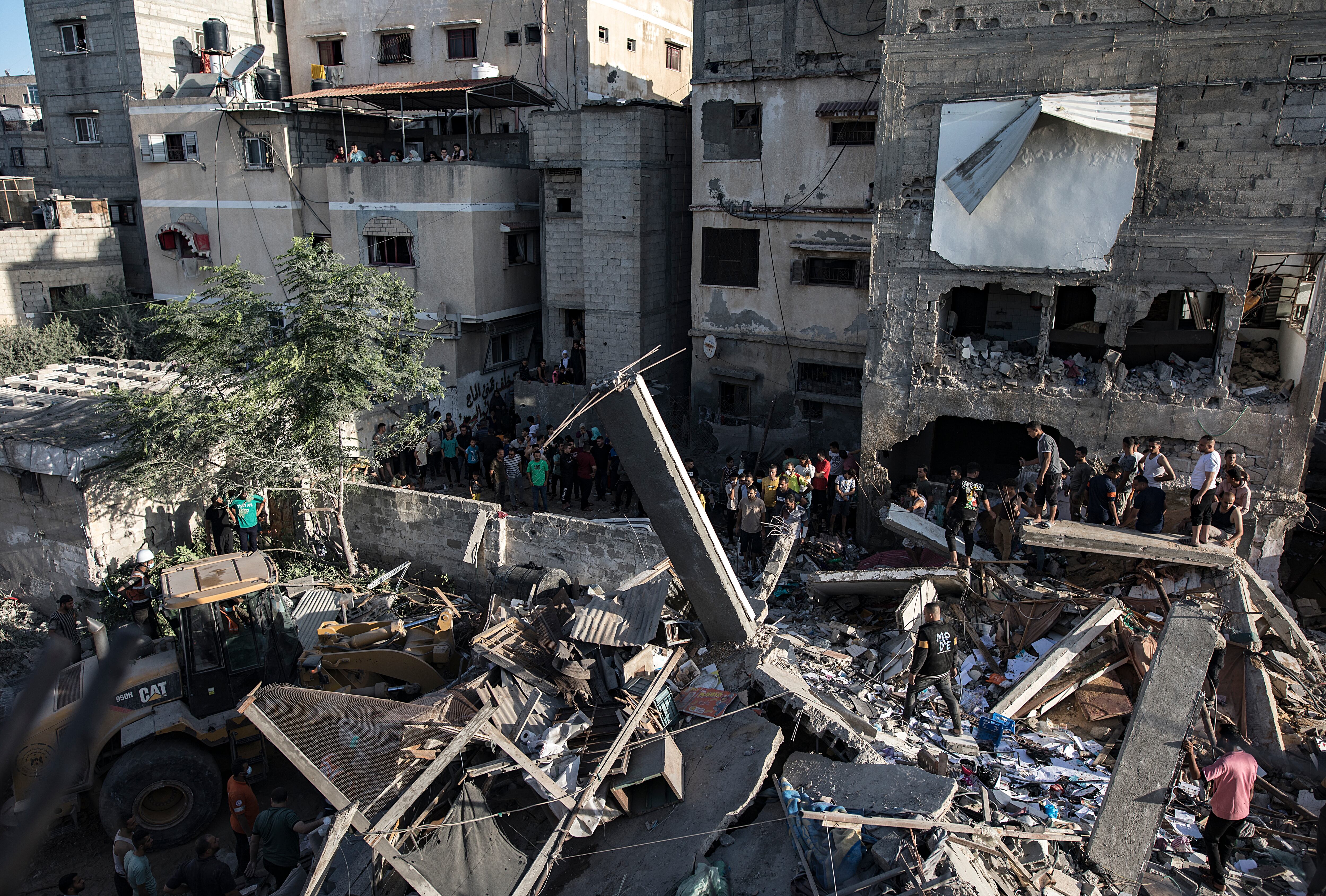 Palestinos buscan cadáveres y supervivientes entre los escombros de un edificio residencial tras un ataque aéreo israelí contra el campo de refugiados de Jan Yunis, en el sur de la Franja de Gaza